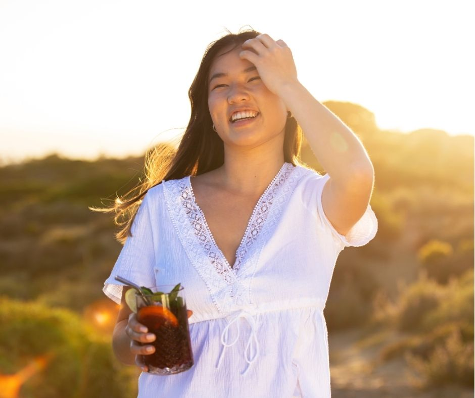 Mujer feliz en verano tomándose un refresco